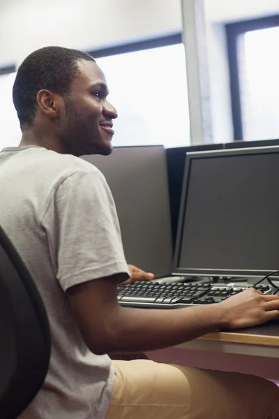 Człowiek siedzi w komputerze uśmiechający się — Zdjęcie stockowe