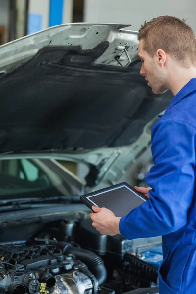 Mecánico con tableta pc examinar el motor del coche — Foto de Stock