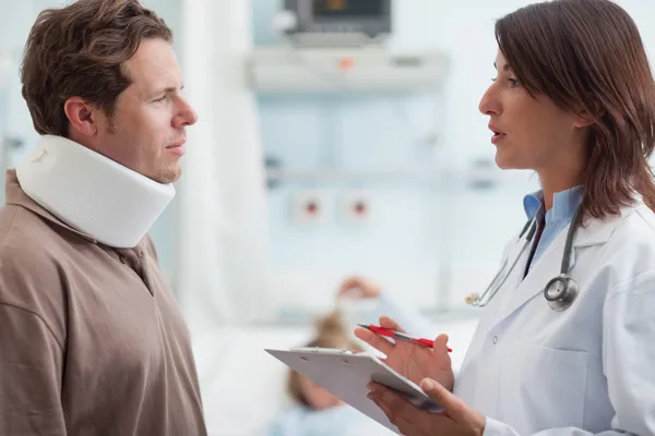 Doctor hablando con un paciente masculino con un collar puesto —  Fotos de Stock