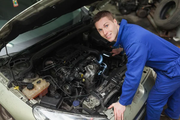 Mecánico feliz examinando el motor del coche Fotos de stock libres de derechos