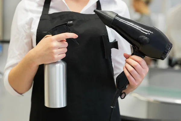 Hairdresser with hair dryer and spray — Stock Photo, Image