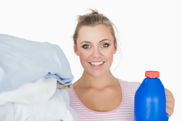 Usmívající se žena s oblečením a prací prášek láhev — Stock fotografie