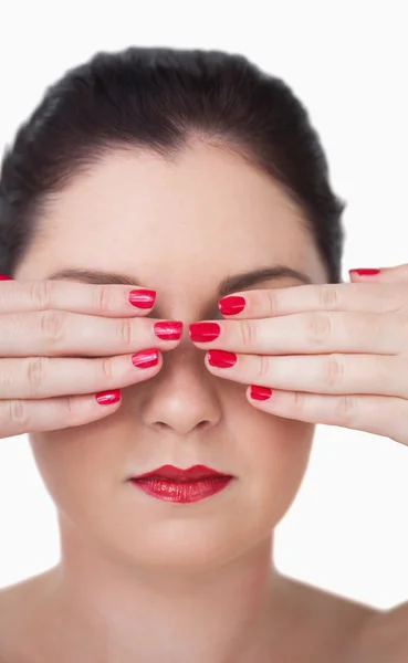 Sensuous young woman covering eyes with red painted finger nails — Stock Photo, Image