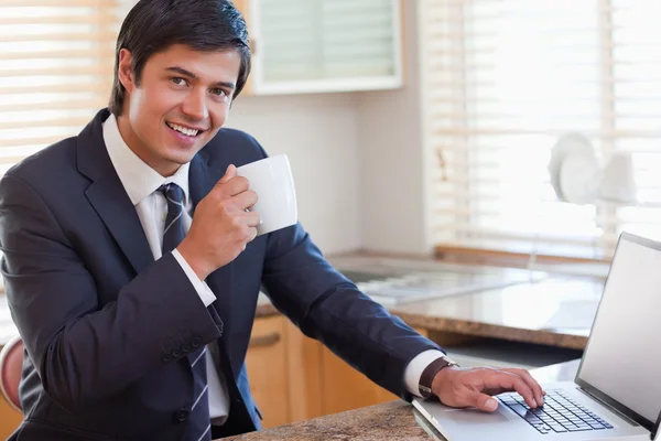 Ο άνθρωπος των επιχειρήσεων χρησιμοποιώντας φορητό υπολογιστή και πίνοντας καφέ — Φωτογραφία Αρχείου