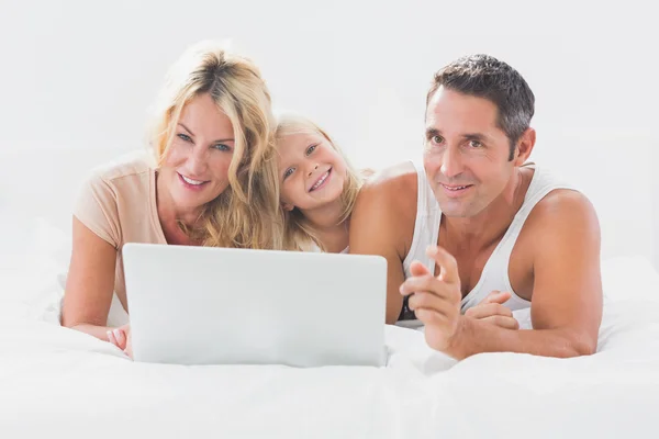 Famille couchée sur un lit avec ordinateur portable — Photo