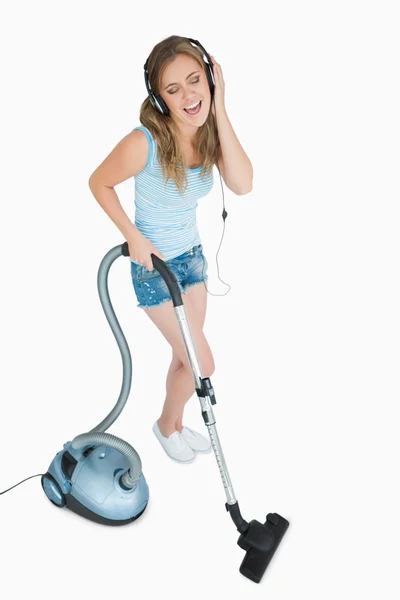 Woman enjoying music over headphones while vacuuming — Stock Photo, Image