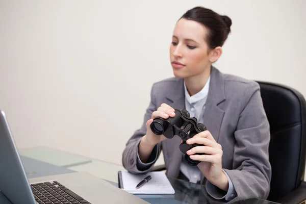 Mujer de negocios con prismáticos mirando el portátil —  Fotos de Stock