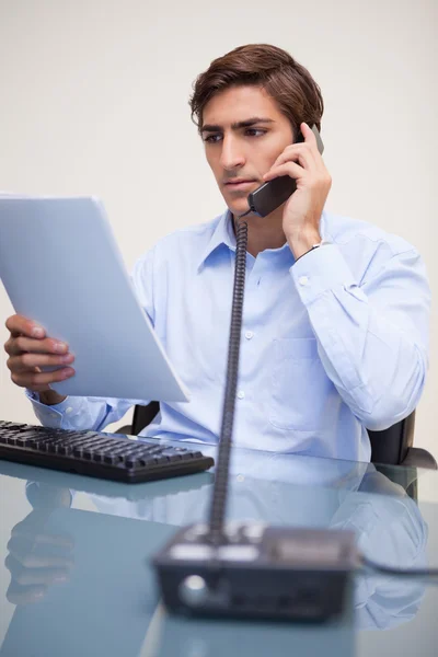 Business man looking at document while on call — Stock Photo, Image