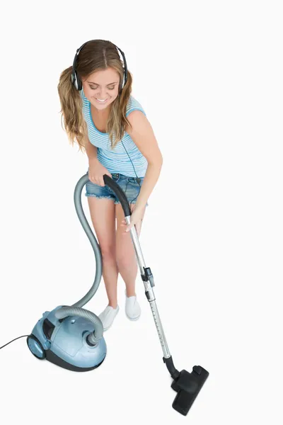 Woman listening music over headphones while vacuuming — Stock Photo, Image