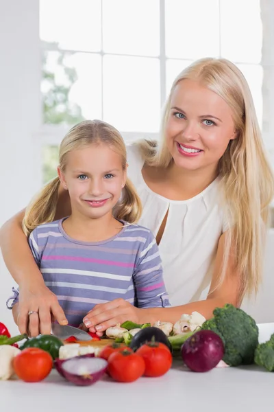 Lachende moeder onderwijs snijden groenten — Stockfoto