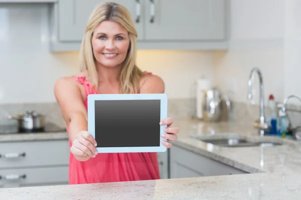 Portrait of casual woman holding out digital tablet in kitchen — Stock Photo, Image