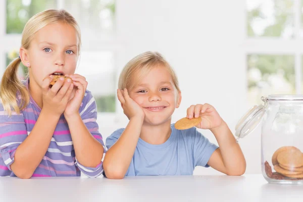 Brother and sister eating biscuits together — Stock Photo, Image