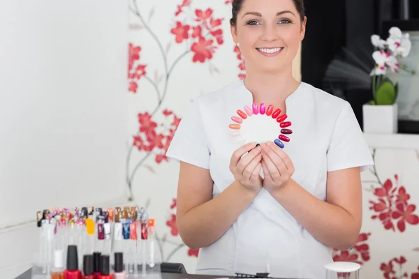 Usmívající se žena drží nehty odstíny v salonu — Stock fotografie