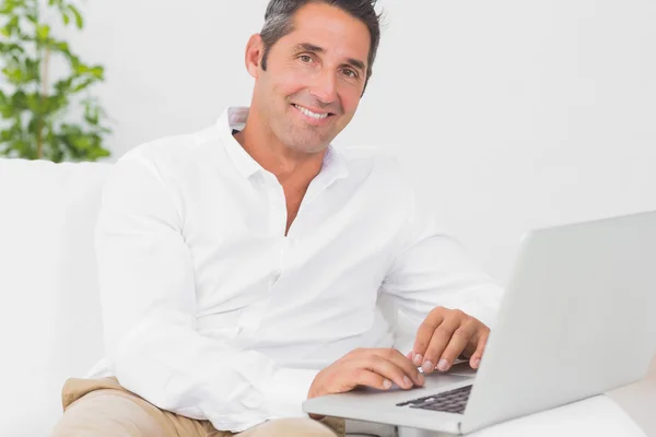Χαμογελαστός άνθρωπος χρησιμοποιώντας φορητό υπολογιστή του — Φωτογραφία Αρχείου