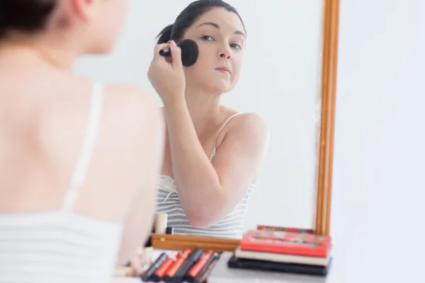 Mujer joven aplicando maquillaje en la cara —  Fotos de Stock