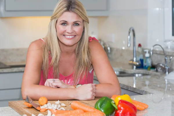 Portret van lachende vrouw met groenten in de keuken — Stockfoto