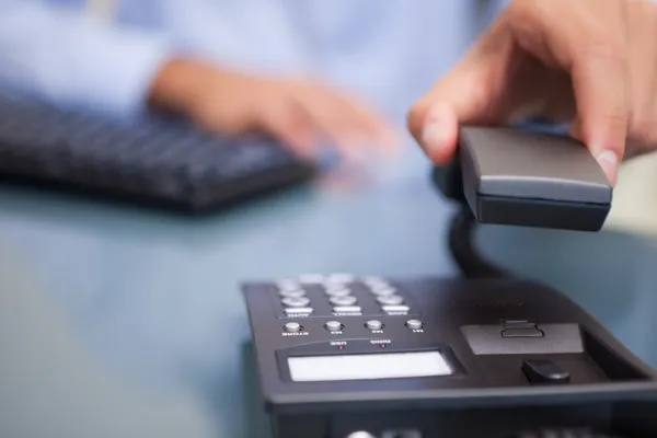 Man with telephone receiver at desk — Stock Photo, Image