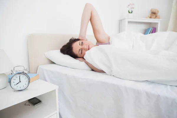 Mujer cubriendo orejas en la cama como anillos de despertador — Foto de Stock