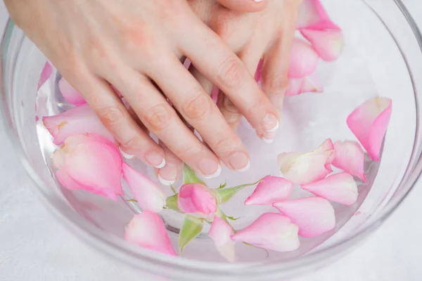 Le mani di donna in boccia con petali a spa di mani — Foto Stock