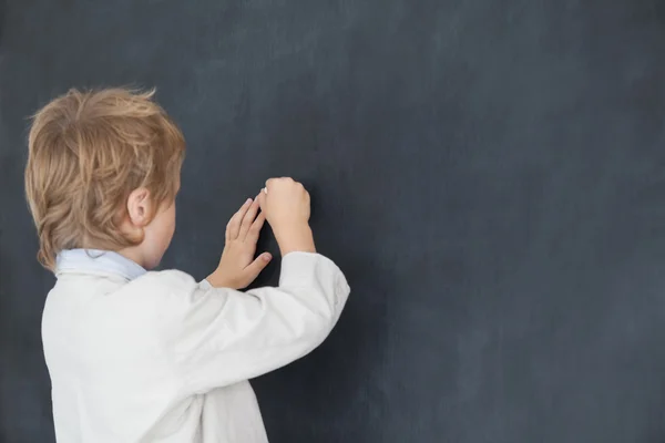 Boy dressed as teacher and writes on black board — Stock Photo, Image