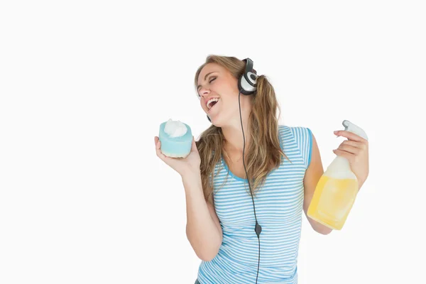 Woman with sponge and spray bottle enjoying music over headphone — ストック写真