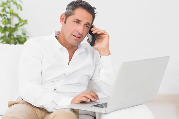 Człowiek za pomocą laptopa i telefon — Zdjęcie stockowe