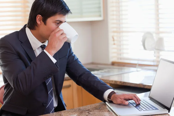 Uomo d'affari che utilizza il computer portatile mentre beve caffè — Foto Stock