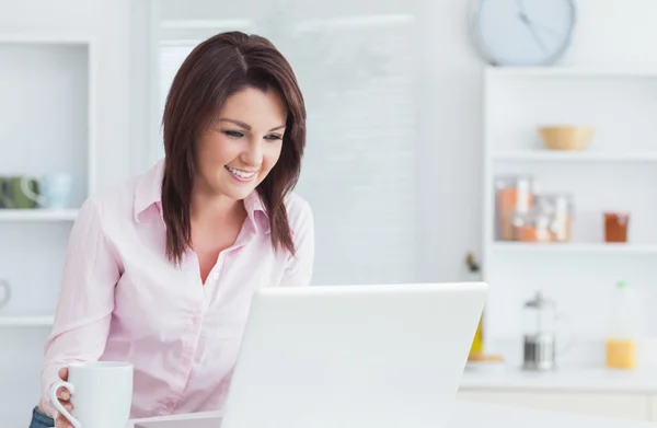 Femme avec tasse de café en utilisant un ordinateur portable à la maison — Photo