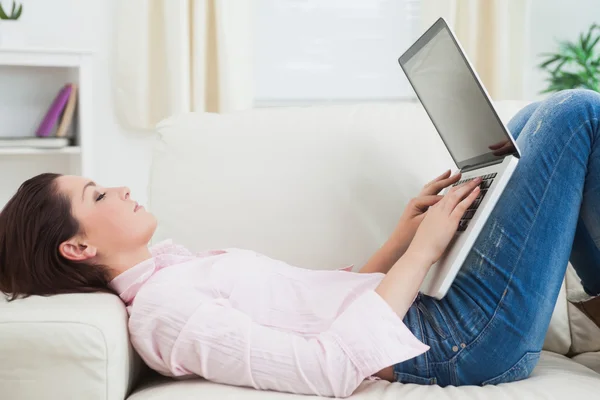 Casual vrouw liggend op de Bank en met behulp van laptop — Stockfoto