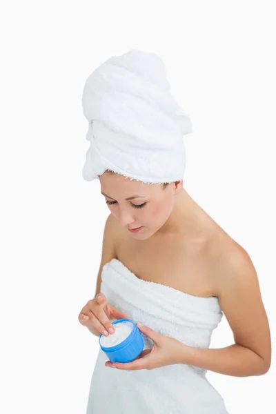 Young woman wrapped in towel applying cream — Stock Photo, Image