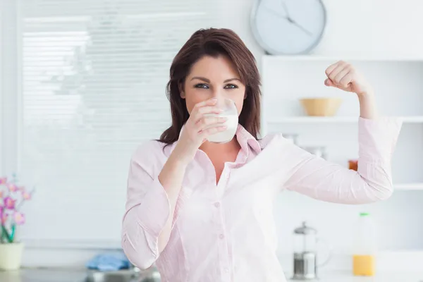 Woman drinking milk and flexing muscles — Stock Photo, Image