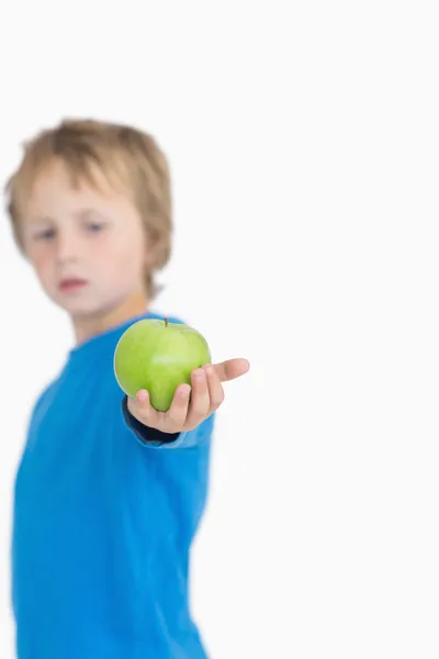 Young boy holding out a green apple — Stock Photo, Image