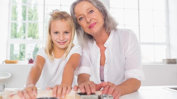 Leende barnbarn att göra kex med hennes mormor — Stockfoto