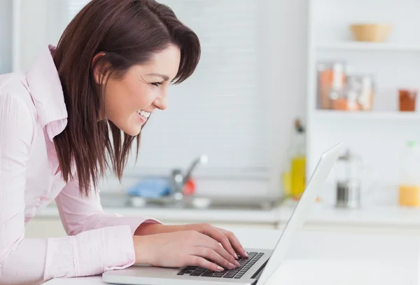 Vista lateral da jovem mulher feliz usando laptop — Fotografia de Stock