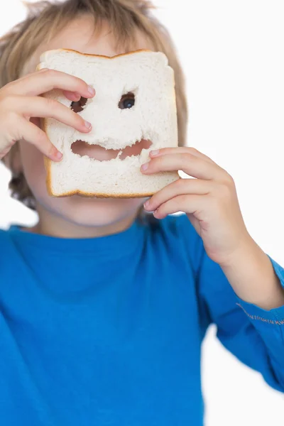 Boy looking through holes in bread slice — Stock Photo, Image