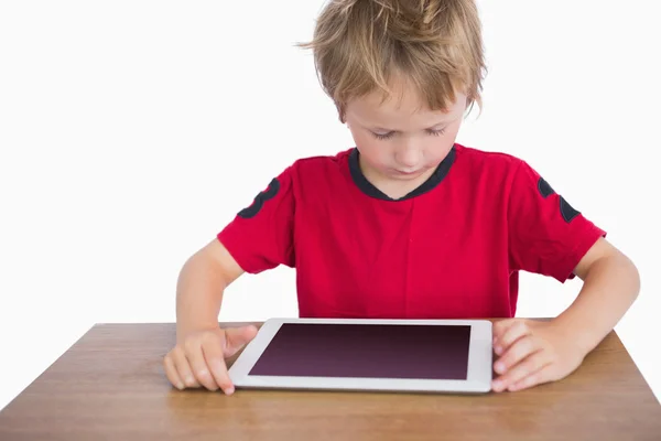 Menino sentado na mesa e olhando para tablet digital — Fotografia de Stock