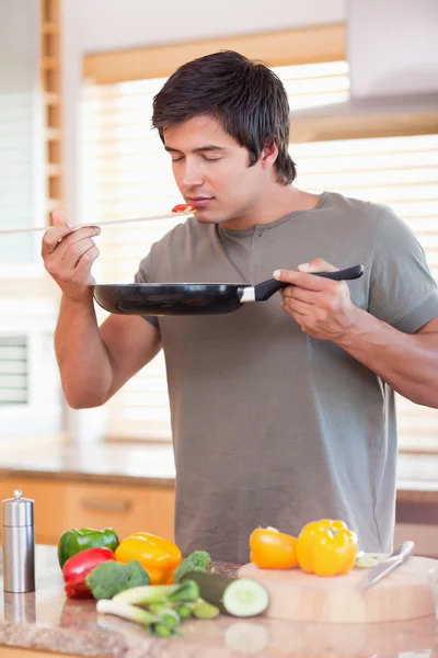 Jovem cheirando comida na cozinha — Fotografia de Stock