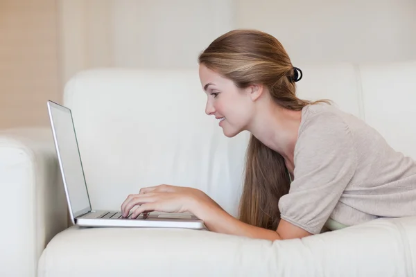 Vista laterale della donna casuale che utilizza il computer portatile sul divano — Foto Stock