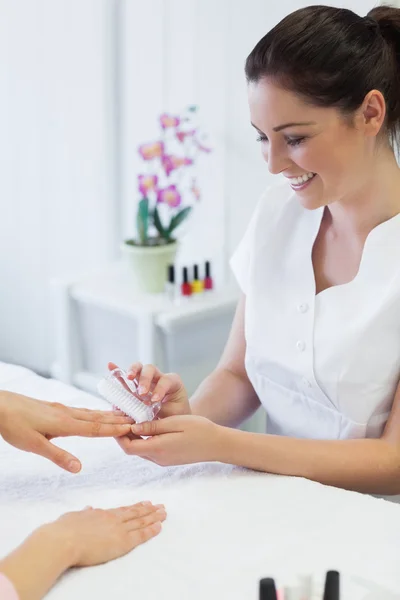 Manicurista con pennello per unghie sulle unghie della donna — Foto Stock