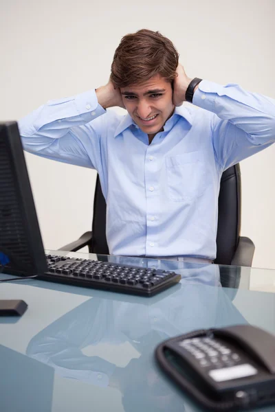 Geschäftsmann verdeckt Ohren am Schreibtisch — Stockfoto