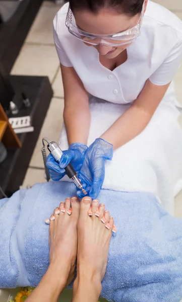 Nail technician removing callus at feet — Stock Photo, Image