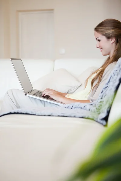 Casual vrouw zittend op de Bank en met behulp van laptop — Stockfoto