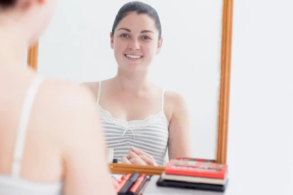 Glad kvinna som tittar på själv i spegel — Stockfoto