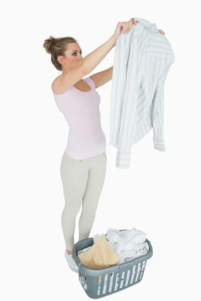 Mujer examinando camisa con cesta de lavandería — Foto de Stock