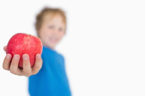 Ung pojke håller ut ett äpple — Stockfoto