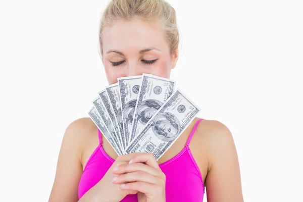 Woman holding fanned banknotes in front of face with eyes closed — Stock Photo, Image