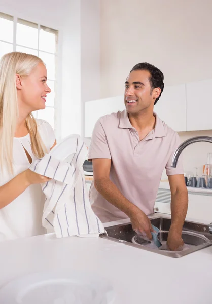 Talking couple washing dishes together — Stock Photo, Image