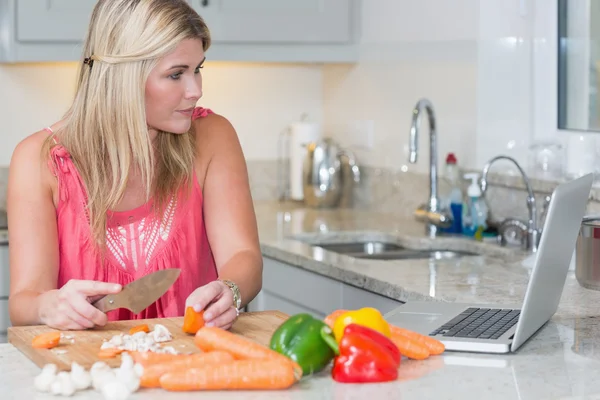 Frau kocht beim Blick auf Laptop — Stockfoto