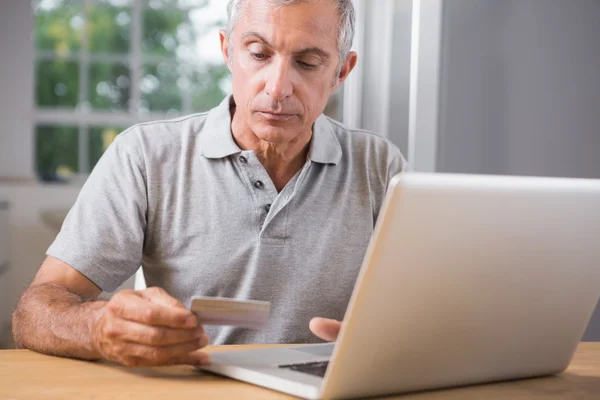 Thoughtful mature man using his laptop — Stock Photo, Image