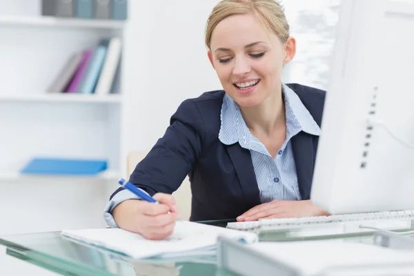 Affärskvinna skriva noter på skrivbord i office — Stockfoto